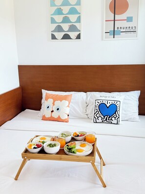 A neatly made bed with a wooden headboard, two decorative pillows, and a tray with breakfast items. - UDOMSAP PLACE (Sattahip)