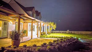 Een huis met een overdekte veranda, een gazon en een houten omheining.