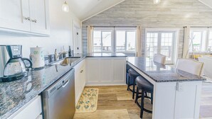 A modern kitchen with white cabinets, granite countertops, and a large island with bar stools. - 3 Oceanfront House in 1: Scopa 5BD + Seaview 3BD + Seasong 2BD* (Crescent City)