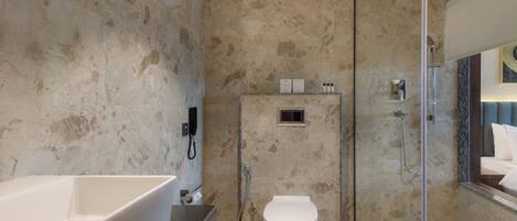 Un baño moderno con una bañera independiente, un inodoro y una zona de ducha con mampara de vidrio.
