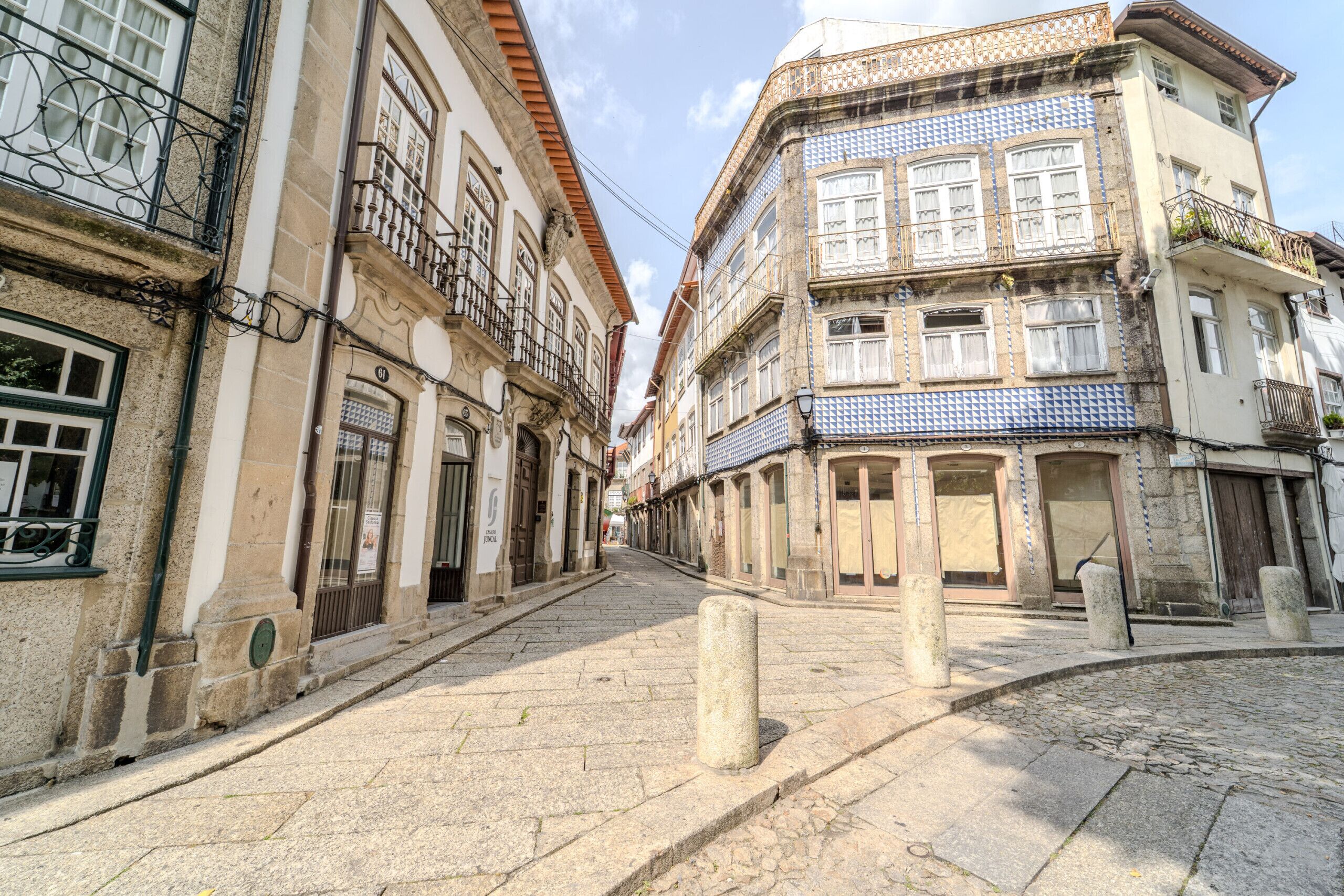 A cobblestone street lined with historic buildings, featuring balconies and traditional architecture.