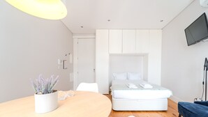 A modern bedroom with a bed, bedside table, and a TV mounted on the wall.