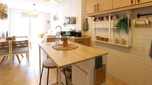 A modern kitchen with wooden cabinets, a central island, and a hanging pot rack.