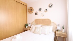 A neatly made bed with white linens and pillows, a wooden wardrobe, and a wall decorated with circular art pieces.
