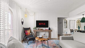 A modern living room with a sofa, a coffee table, and a TV displaying 'NETFLIX'. - The Abuela House w/ pool Near Airport & Ft Moore (Columbus)