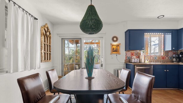 A dining area with a round table, six chairs, a decorative vase, and a green pendant light. - The Abuela House w/ pool Near Airport & Ft Moore (Columbus)