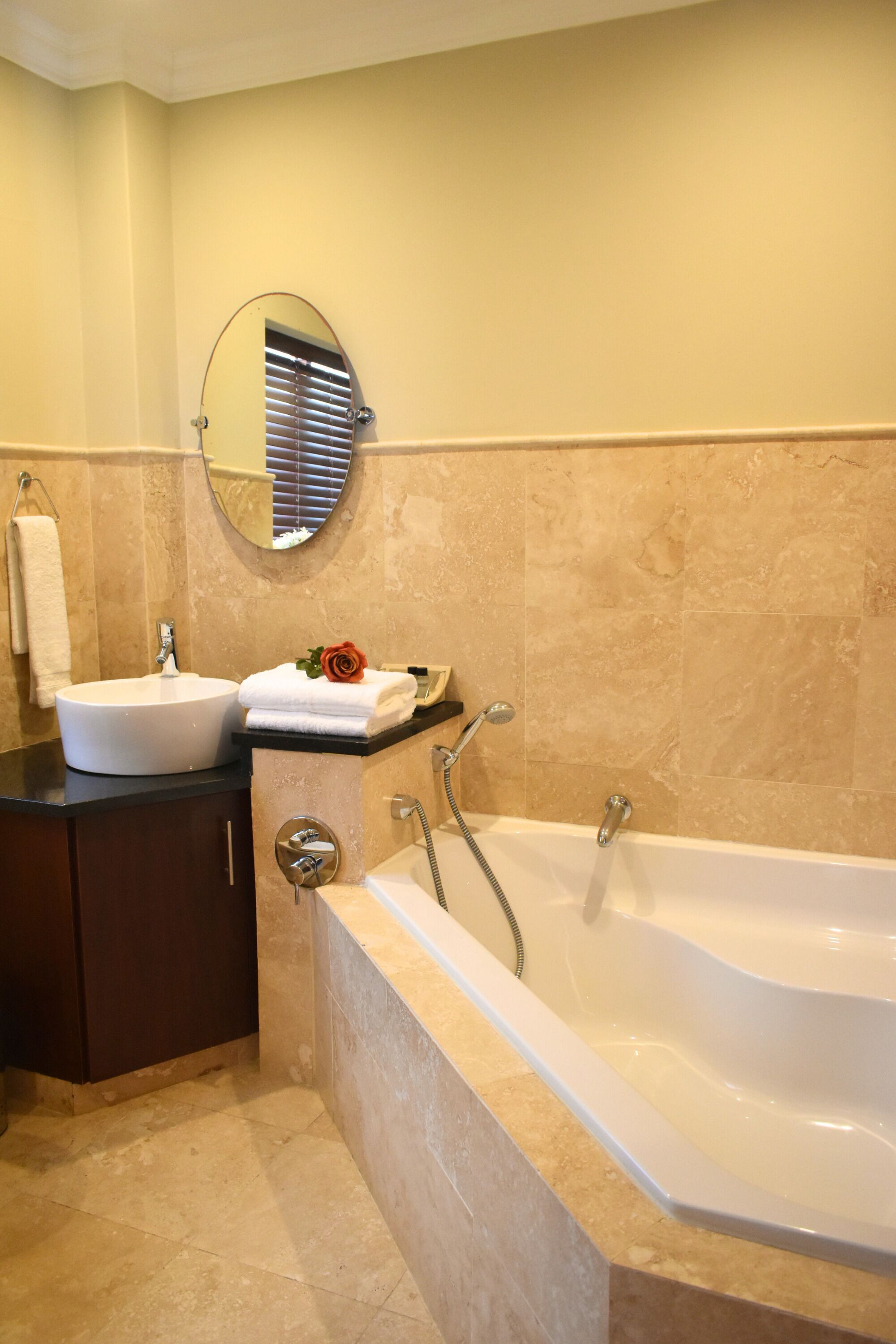 A bathroom with a sink, mirror, towel rack, and bathtub.