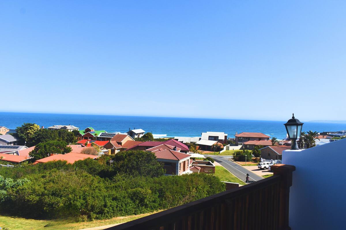 A coastal residential area with houses, a street, and a view of the ocean.