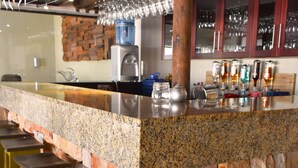 A bar area with a granite countertop, stone walls, and wooden stools. - Bergwood Inn (Groot Brakrivier)