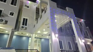 A multi-story building with balconies and a central archway adorned with blue lights. - Camas Hotels  (Abeokuta)