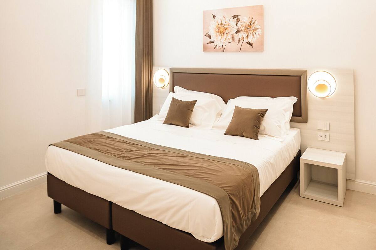 A modern bedroom with a large bed, bedside lamps, and a ceiling light.