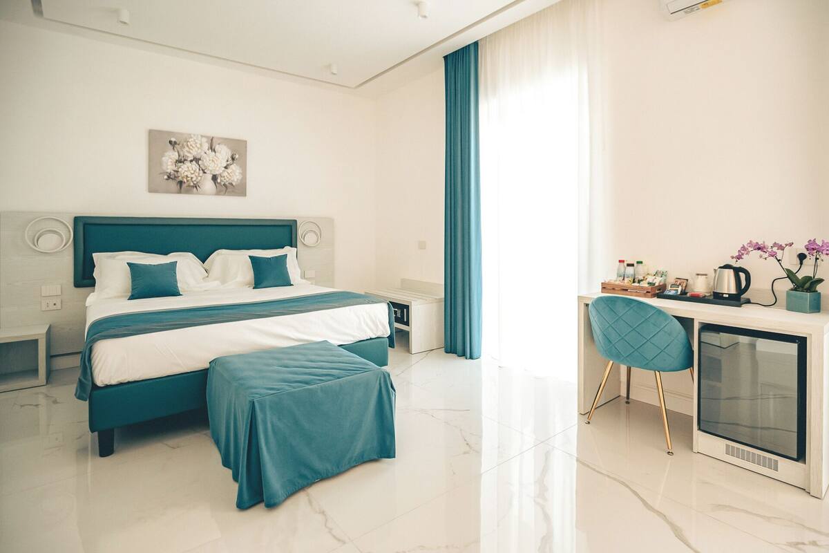 A modern hotel room with a large bed, a desk, and a chair.