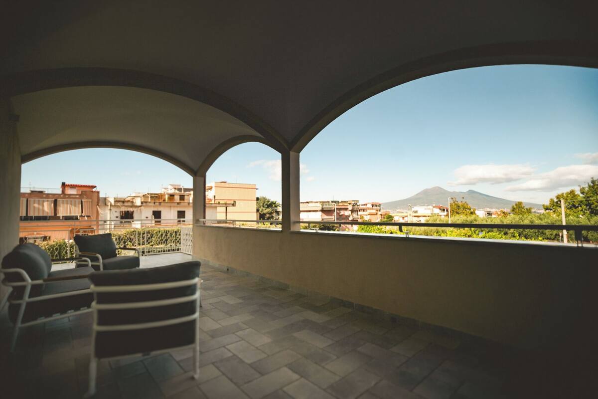 A covered outdoor area with a view of buildings and a mountain in the distance.