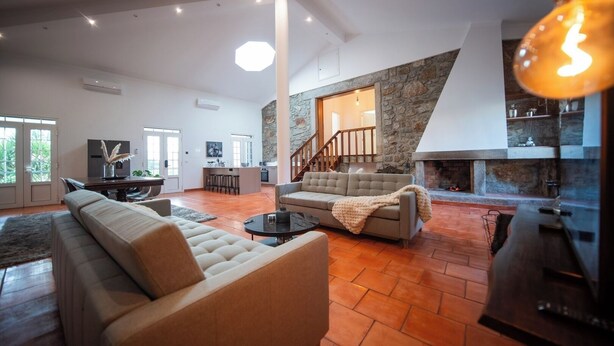 Amplia sala de estar con chimenea, un sofá y una mesa de comedor.