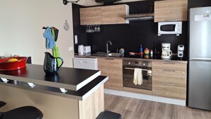 A modern kitchen with wooden cabinets, a stainless steel refrigerator, a microwave, and a dishwasher.