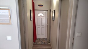 A hallway with a patterned floor, a white door, and a red curtain.