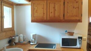 A compact kitchen with wooden cabinets, a microwave, a coffee maker, and a sink. - Studio 3 ppl - Ski-in/ski-out - Val d'Isère Center - Wifi (Val-d'Isère)