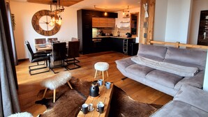 A modern living room with a grey sofa, wooden coffee table, and a large round wall clock. - Cozy apartment in Les Gets, 3 bedrooms, Wi-Fi (Les Gets)
