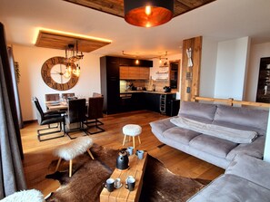 A modern living room with a grey sofa, wooden coffee table, and a large round wall clock. - Cozy apartment in Les Gets, 3 bedrooms, Wi-Fi (Les Gets)