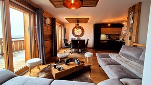 A modern living room with a sofa, a wooden coffee table, and a dining area with chairs. - Cozy apartment in Les Gets, 3 bedrooms, Wi-Fi (Les Gets)