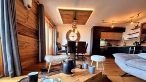 A cozy living room with a wooden coffee table, a sofa, and a dining area with chairs and a table. - Cozy apartment in Les Gets, 3 bedrooms, Wi-Fi (Les Gets)
