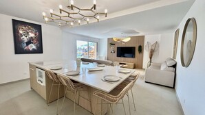Une cuisine moderne dotée d’un îlot central, de chaises de salle à manger, d’un four encastré et d’une grande fenêtre offrant une vue sur l’extérieur.