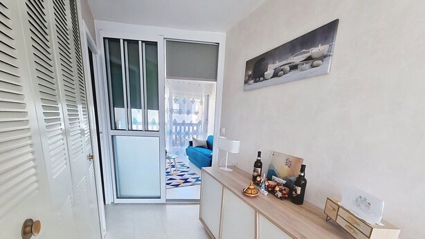 A modern kitchen with a wooden countertop, a blue sofa, and a dining area with a patterned rug. - Cozy apartment 4 pax near sea with parking (Courseulles-sur-Mer)