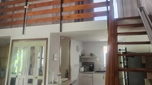 Habitación estilo loft con techo de madera, kitchenette, comedor y escalera.
