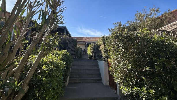 A staircase leading to a building with a tiled roof, surrounded by greenery. - 3-room Pavilion with Terrace, Near the Beach (Narbonne)