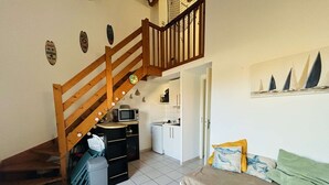 A compact living space with a staircase, kitchenette, and a bed. - 3-room Pavilion with Terrace, Near the Beach (Narbonne)