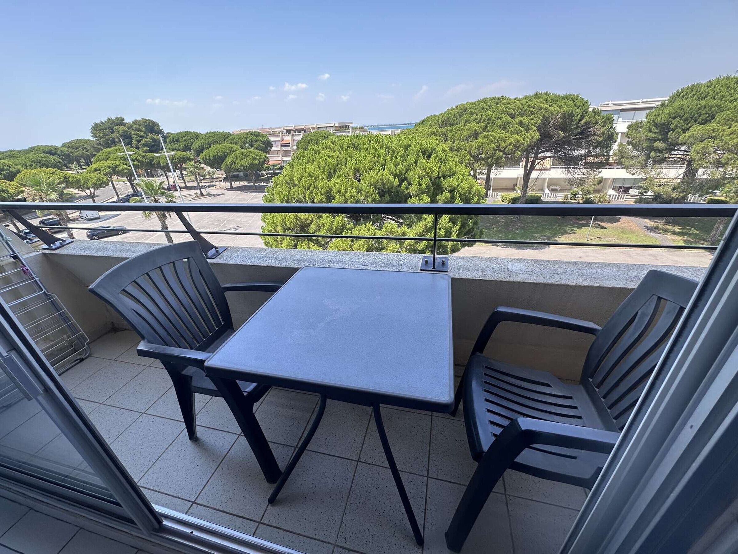 Un balcon avec une table et des chaises, d’où l’on peut admirer un quartier r ésidentiel avec ses arbres et ses immeubles.
