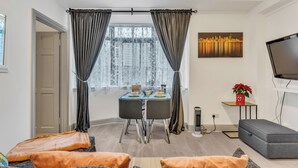 Un salon moderne avec une table à manger, un canapé gris et un téléviseur.