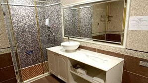 Un bagno moderno con cabina doccia in vetro, lavandino bianco e un ampio specchio.