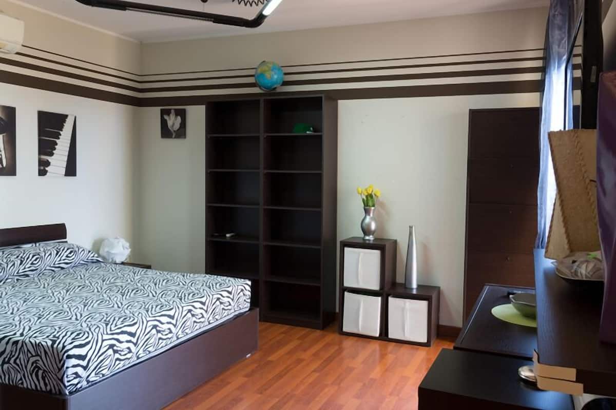 Un dormitorio con cama, armario, escritorio y un globo en la pared.