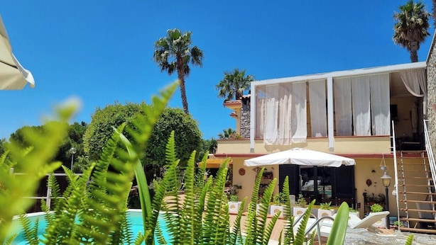 Zona junto a la piscina con un edificio que tiene ventanas grandes y un balcón.