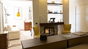 Una sala de estar con chimenea, un sofá, una mesa de centro y una guitarra colgada en la pared.