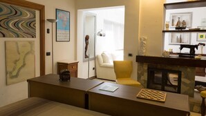 Una sala de estar con chimenea, un sofá, una mesa de centro y un tablero de ajedrez.