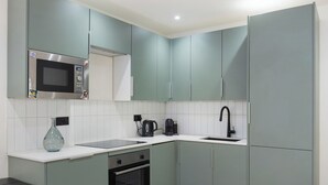 Una cocina pequeña con gabinetes color turquesa, un microondas, un lavamanos y una estufa.