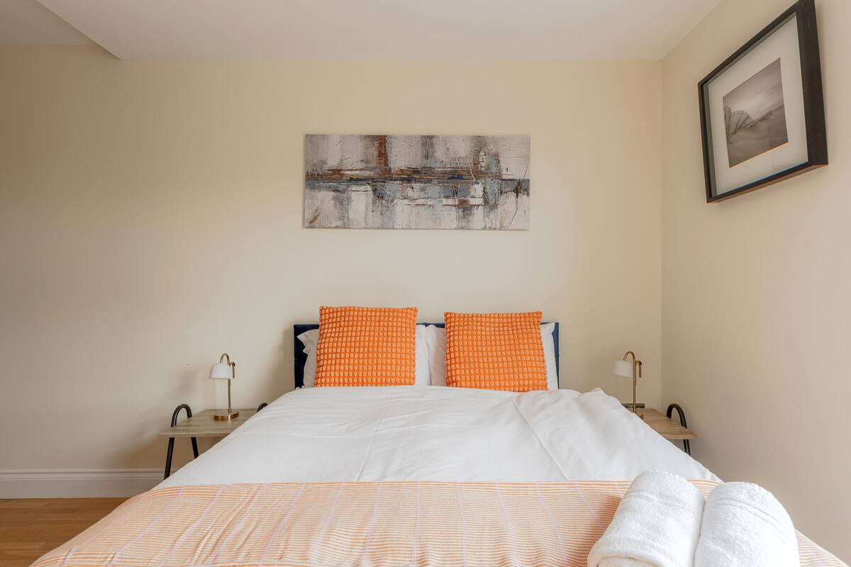 A hotel room with a bed, two nightstands, a framed picture on the wall, and a window.