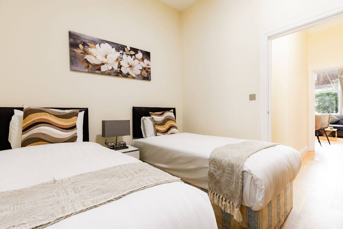 A hotel room with two beds, a nightstand with a lamp, and a painting on the wall.
