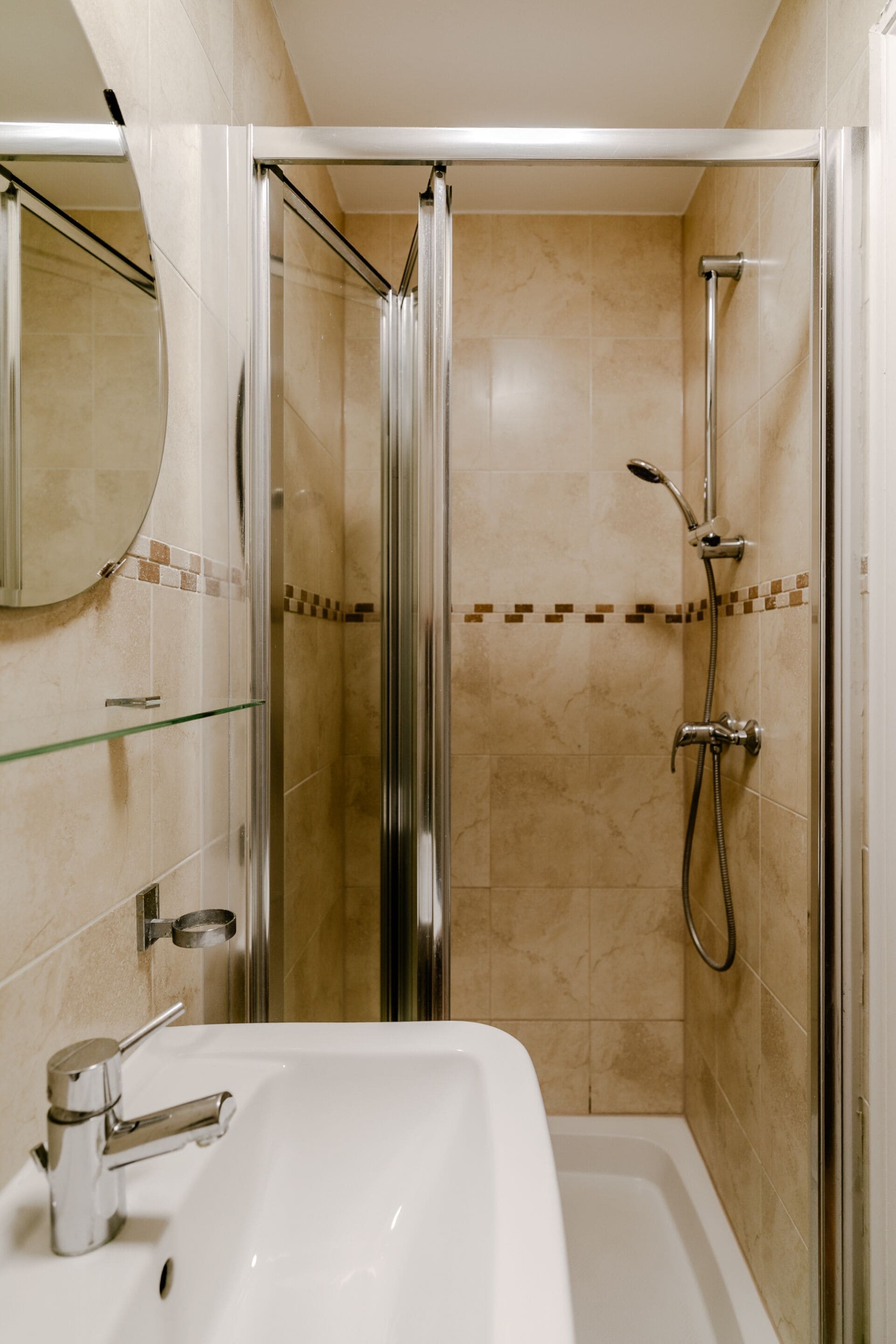 Une salle de bain avec une douche à parois de verre, un lavabo blanc et un miroir.