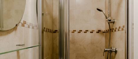 Une salle de bain avec une douche à parois de verre, un lavabo blanc et un miroir.
