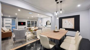 A modern dining area with a wooden table, white chairs, and a black and white abstract painting on the wall.
