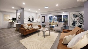 A spacious living area with a brown leather sofa, a coffee table, and a large rug. There is a dining area with chairs and a table, and a kitchen area with a counter and sink.