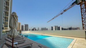 Ein Pool auf dem Dach mit Liegestühlen und Blick auf die Skyline der Stadt.
