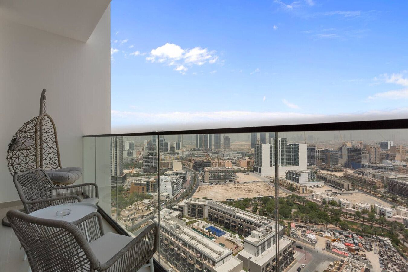 Un balcón con vista a la ciudad, una silla colgante y una mesa.