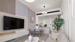 Ein modernes Wohnzimmer mit einem Flachbildfernseher, einem Essbereich und einer Küche im Hintergrund.