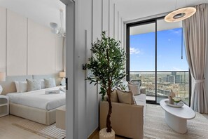 Une chambre d’hôtel moderne avec un lit, un coin salon, une plante et une vue sur la ville.