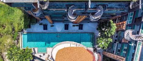 Eine Vogelperspektive eines Hotels mit Schwimmbad, mehreren Balkonen und einer Dachterrasse.