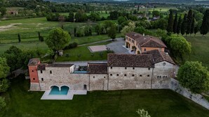 An aerial view of a historic building with a swimming pool, surrounded by lush greenery and fields. - Corte Baruzzo Relais (Volta Mantovana)